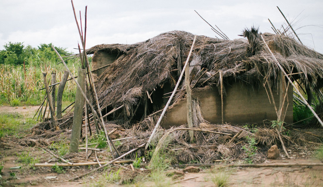 a home with straw roof caved in from a natural disaster