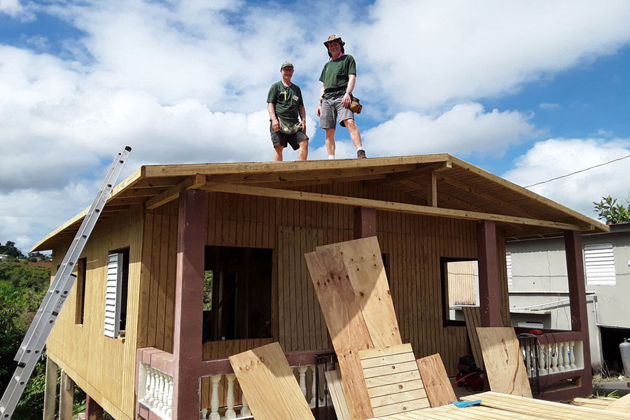 world renew volunteers standing on top of a roof of a home they are rebuilding