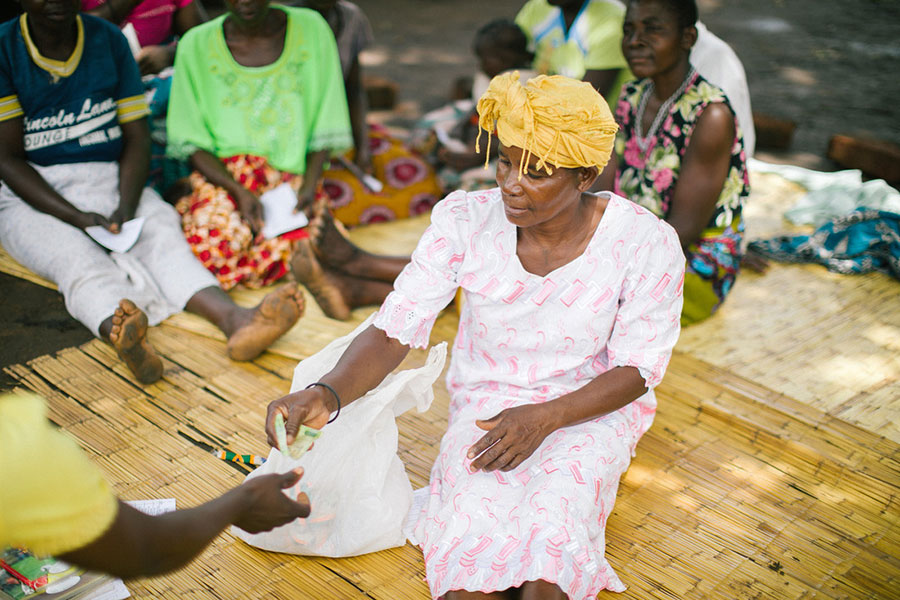 a woman sitting on the center of a bamboo mat handing over cash