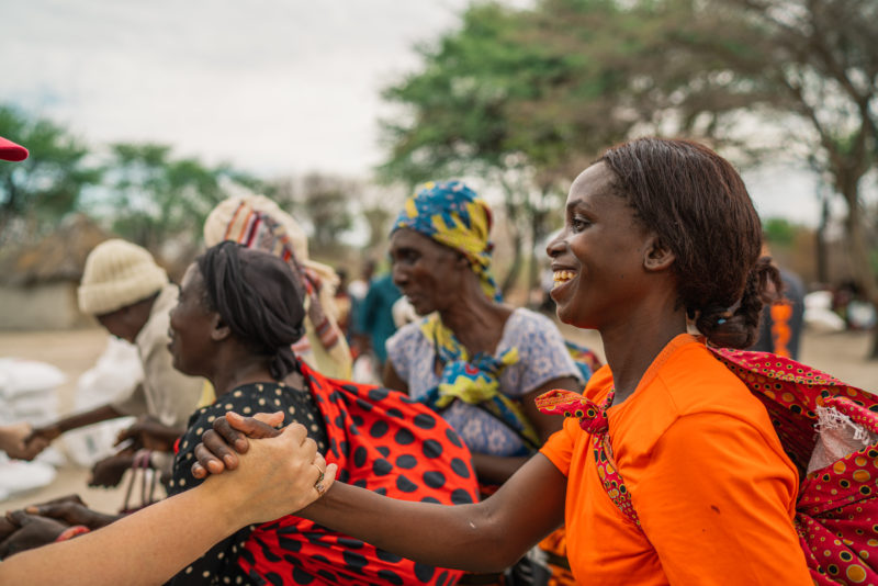RS32860_Zambia PD IDR-Nov 2019-HIGHRES-223 woman greeting friend with handshake and smile advocate for peace and justice work