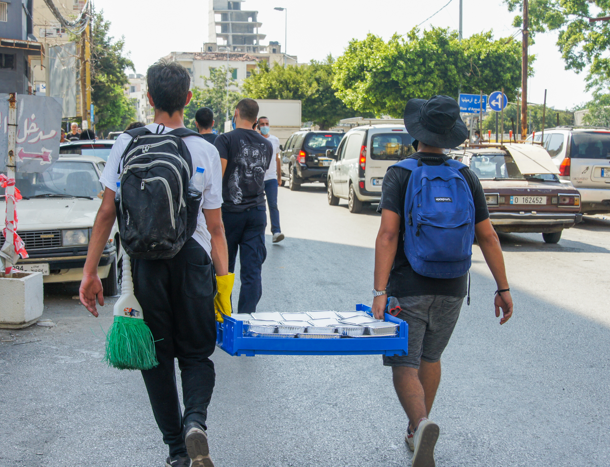 Volunteers in Beirut backs of men pictured carrying a pallet of meals to be given out in beirut