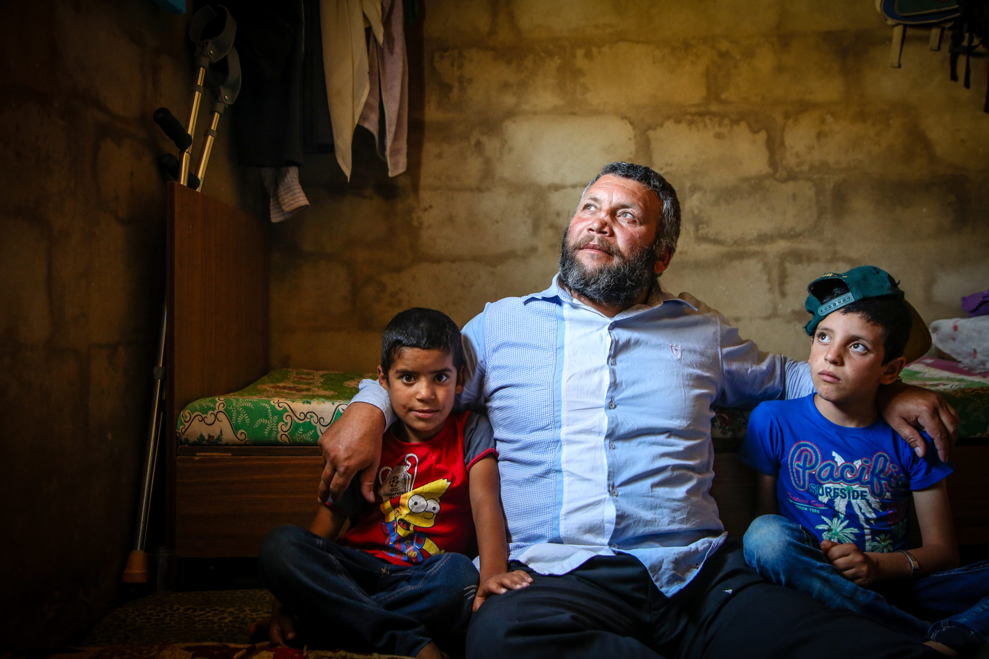 Lebanese man sitting on the ground with his arms around two sons