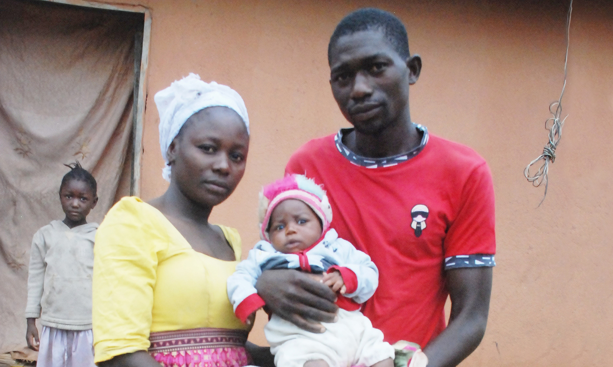 Close up photo of a Nigerian man, woman and baby with a girl in the background