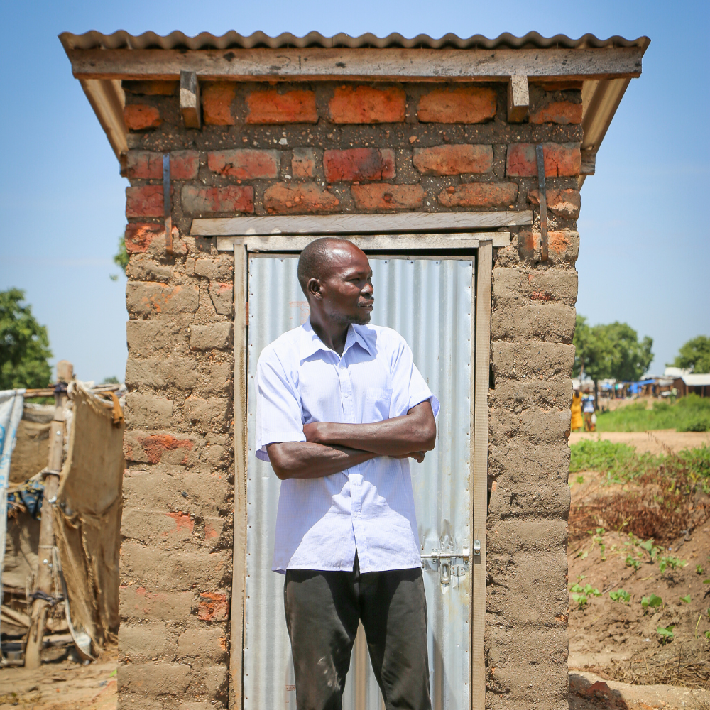 A man stands in front of a latrine