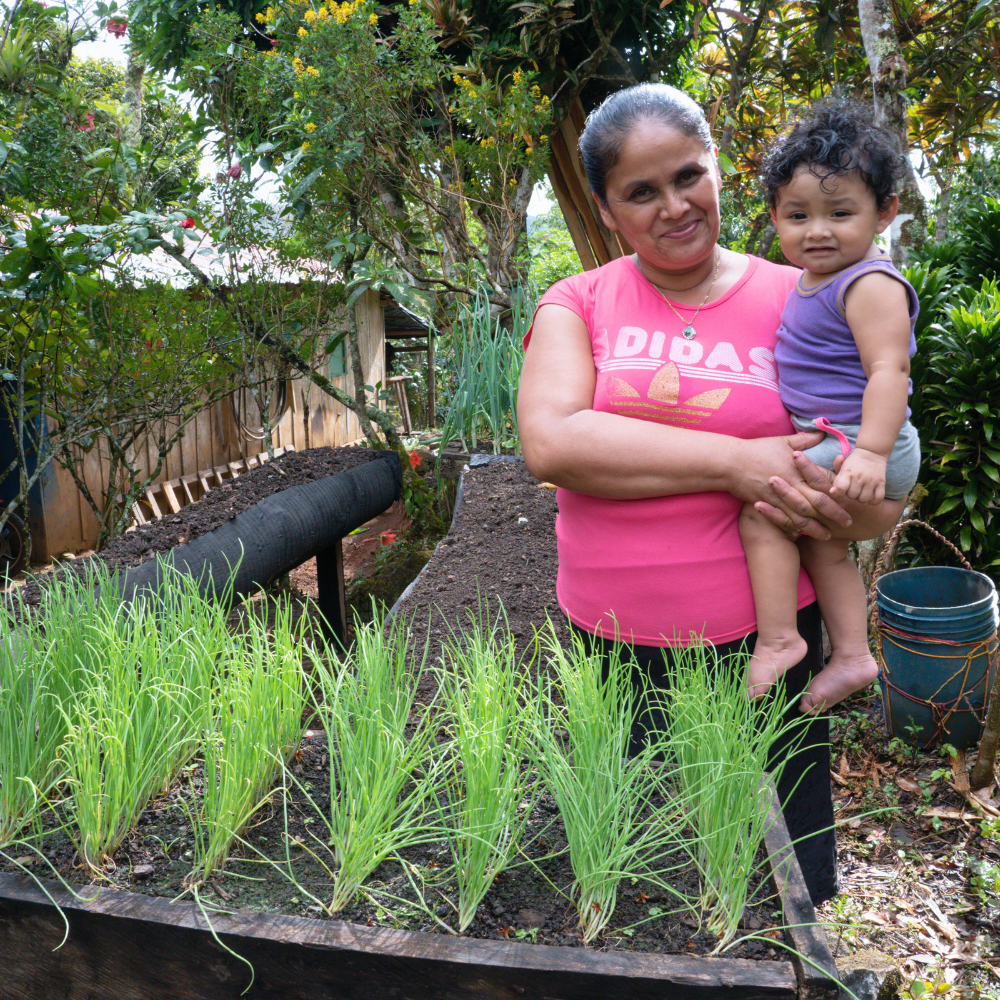 A grandmother and her grandson in front of a garden.