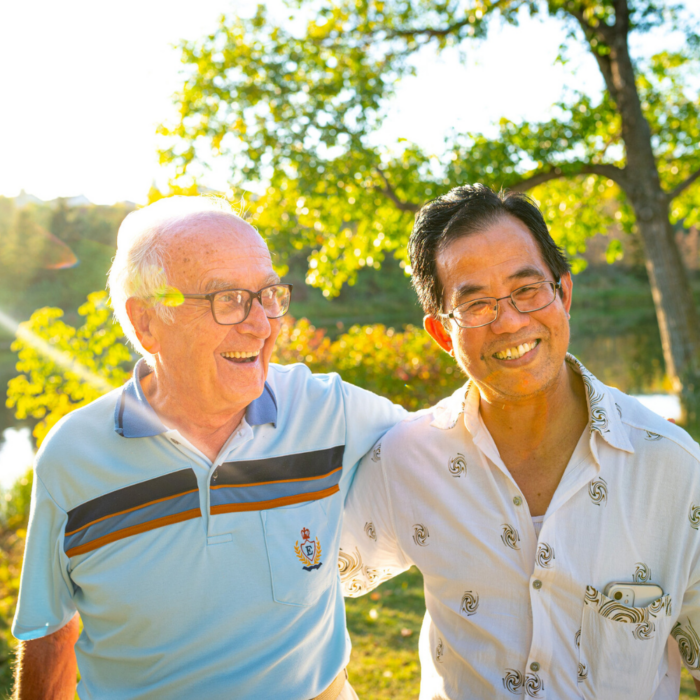 Two men stand arm in arm