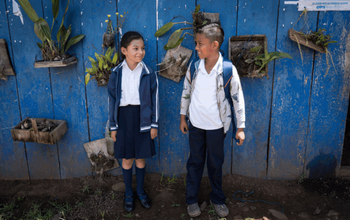 School children stand in front of a wall