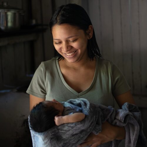 Honduran mother smiling down at her newborn baby.