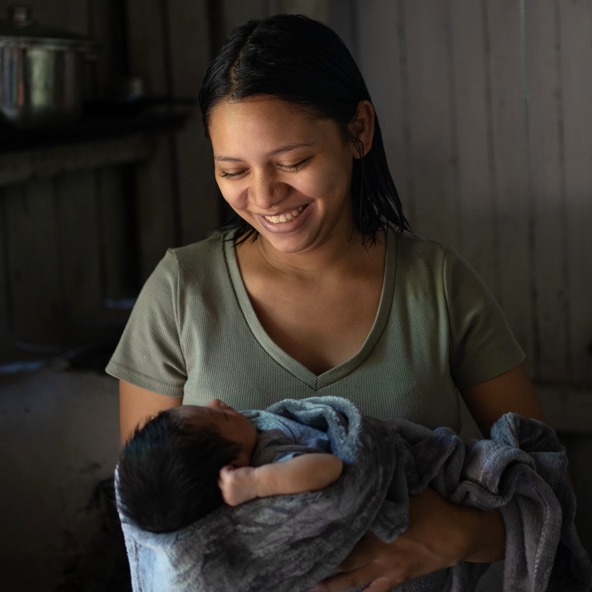 Honduran mother smiling down at her newborn baby.