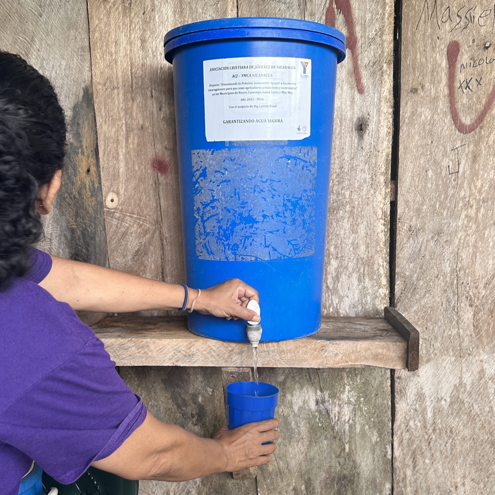 A woman fills a cup from a water filter