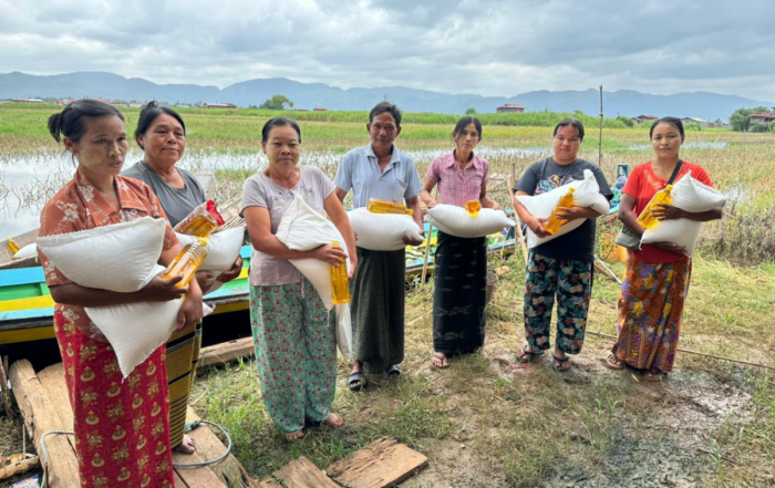 Recipients hold bags of food and oil