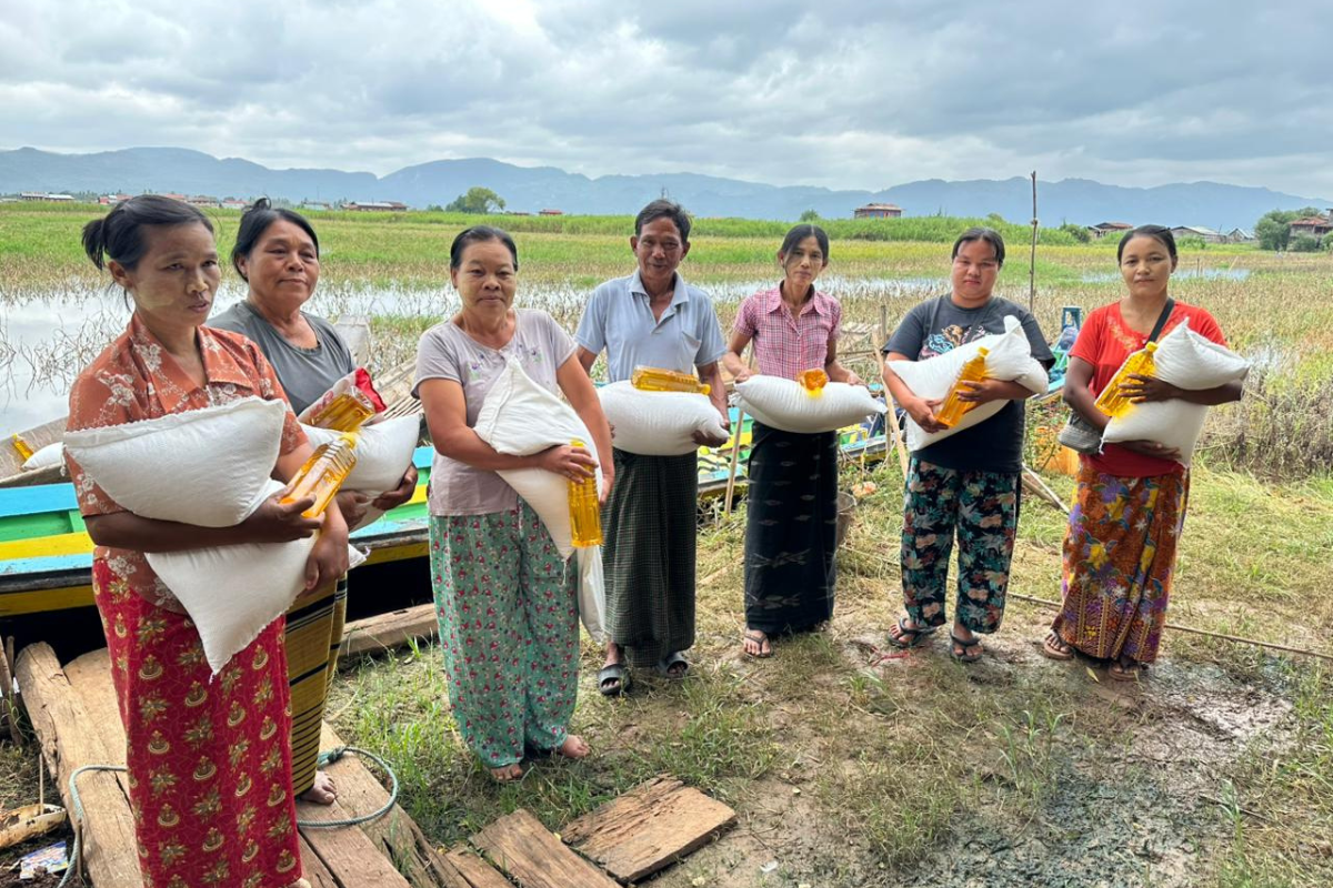 Recipients hold bags of food and oil