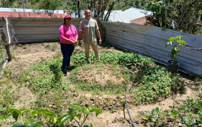 A female farmer stands with her circular garden.