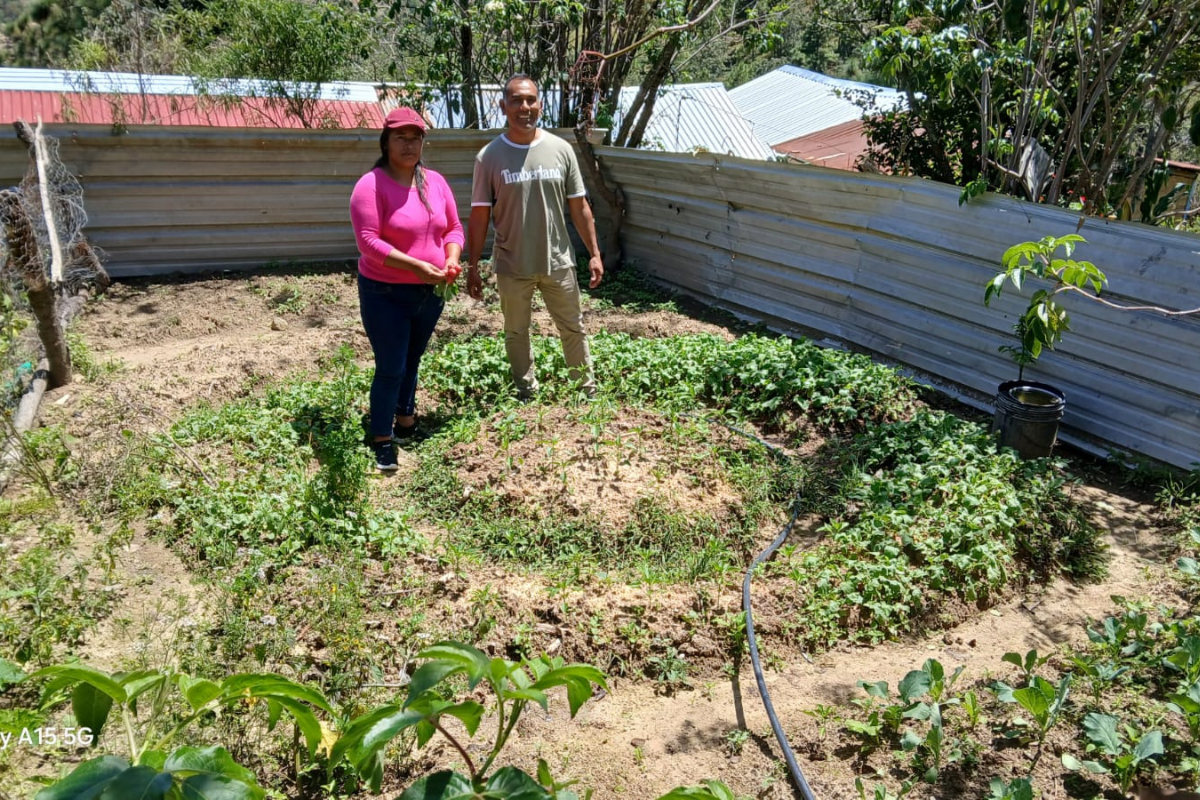 A female farmer stands with her circular garden.